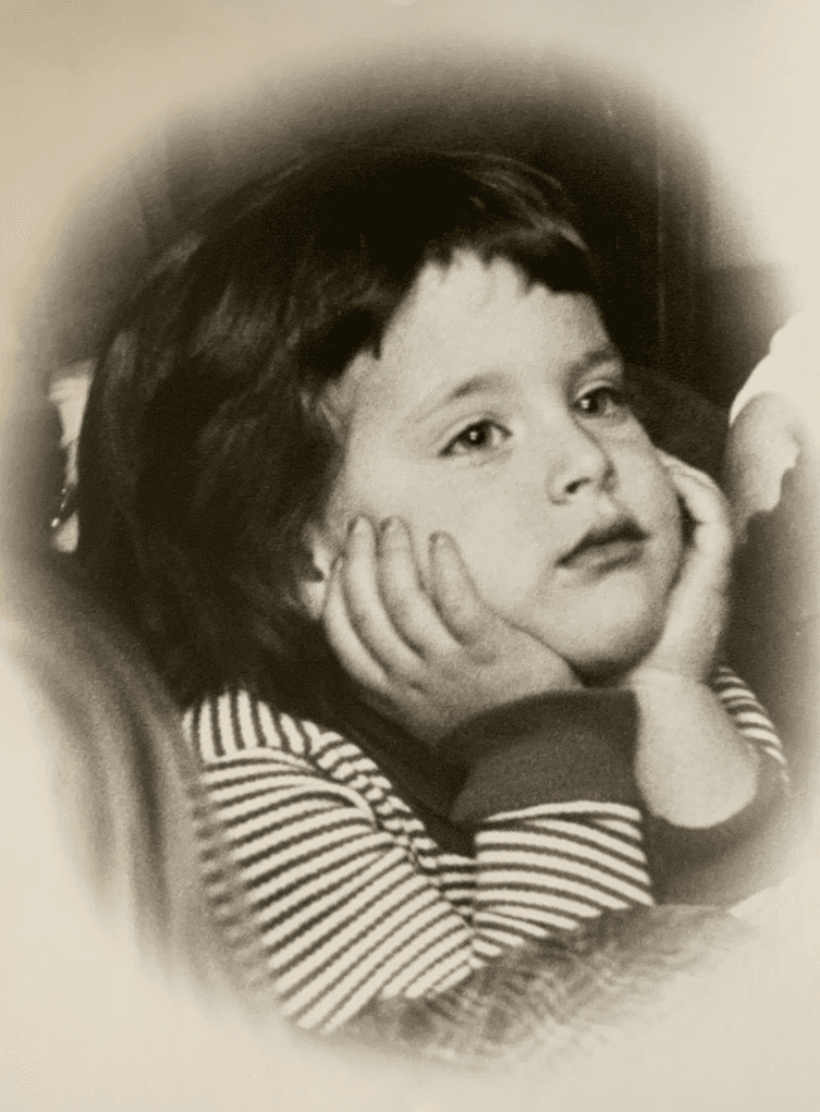 A vintage black and white photo of a young child resting their head on their hands, looking thoughtful.