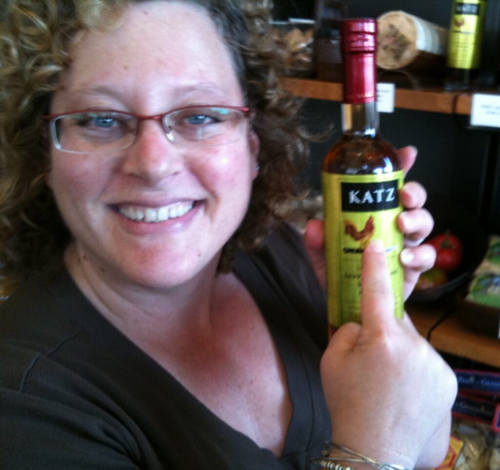 A Woman in Glasses Holding Out a Katz Bottle