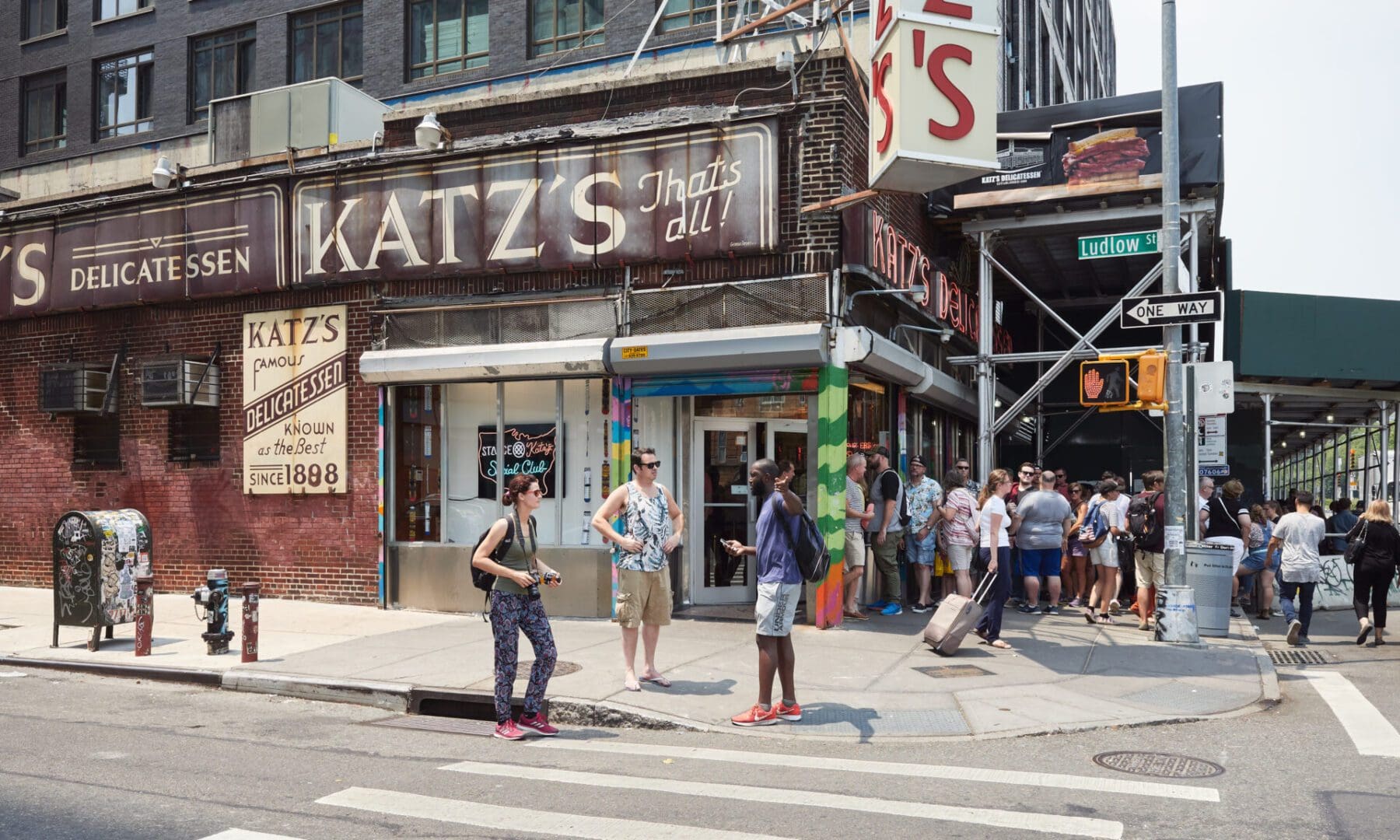 People waiting outside katz's delicatessen on a sunny day at the corner of houston and ludlow streets, nyc.