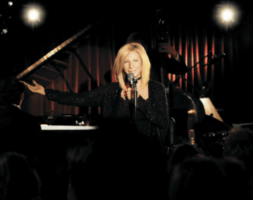 A woman singing into a microphone in front of a crowd.