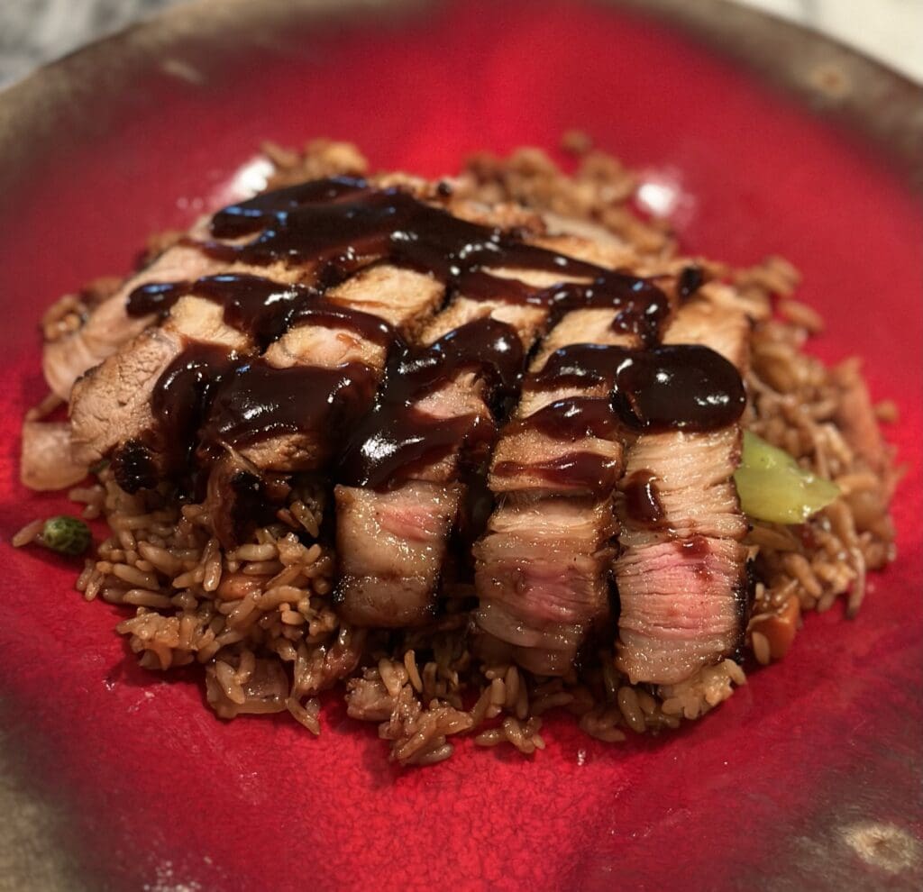 A red plate with meat and rice on it.
