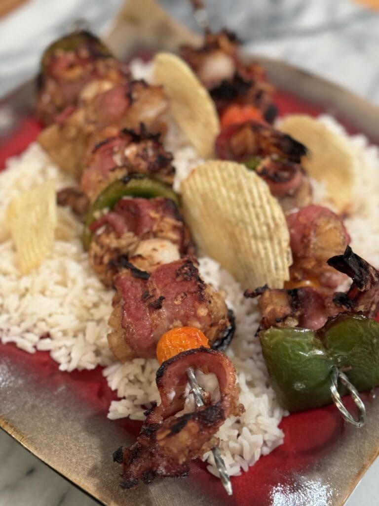 Bacon skewers with rice and peppers on a plate.
