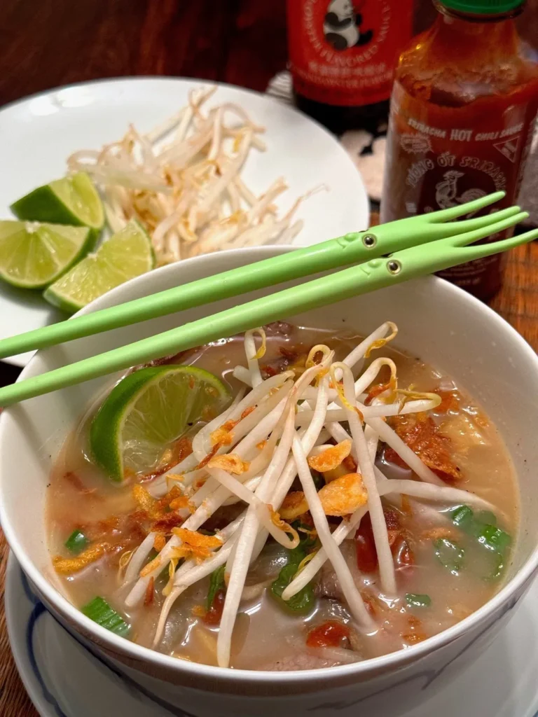 Bowl of soup with bean sprouts and lime.