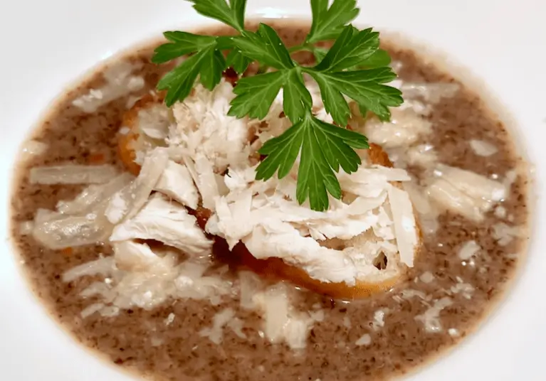 Bowl of chicken soup with herbs.