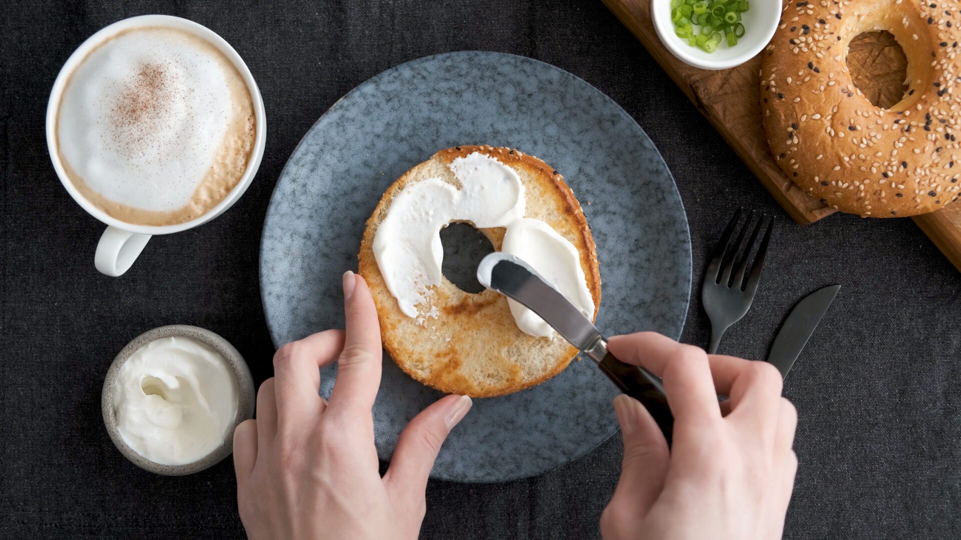 Spreading cream cheese on bagel. Healthy tasty breakfast food. Top view