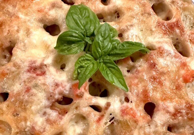 A pasta dish with a basil leaf on top.