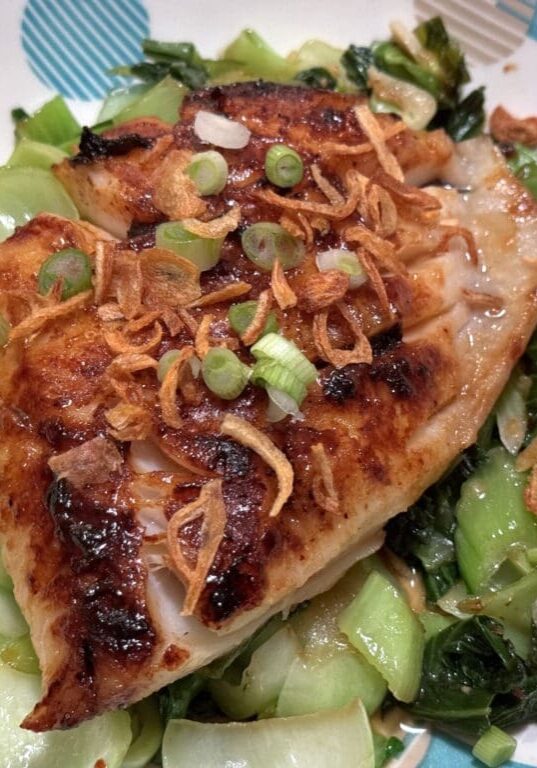 Grilled fish with bok choy and crispy onions.