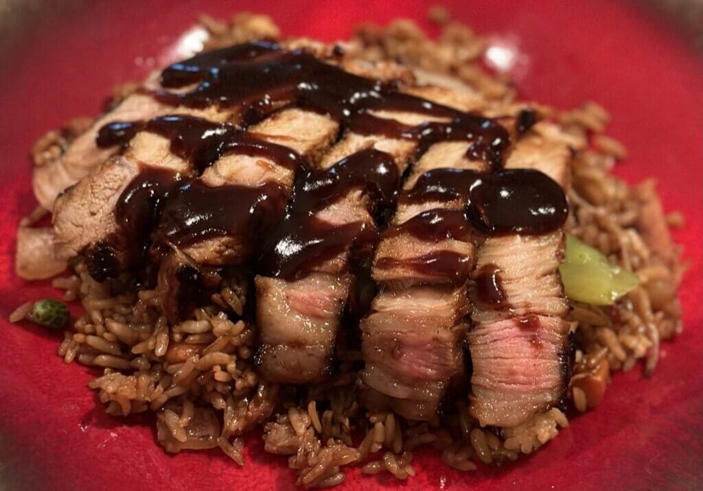 A red plate with meat and rice on it.
