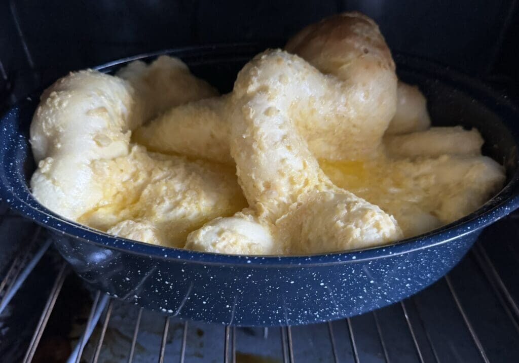 Dutch baby pancake in a speckled pan, rising unevenly in an oven.