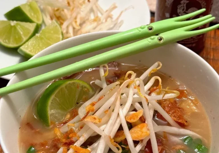 Bowl of soup with bean sprouts and lime.