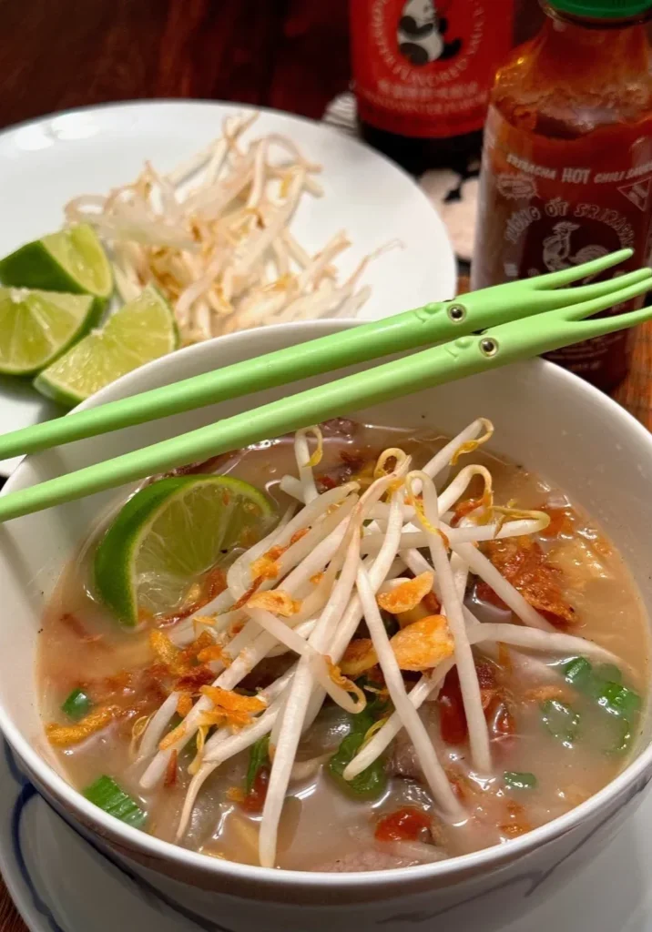 Bowl of soup with bean sprouts and lime.