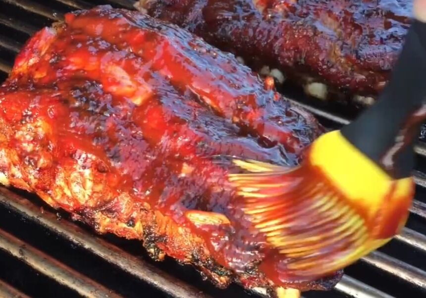 BBQ ribs being basted on a grill.