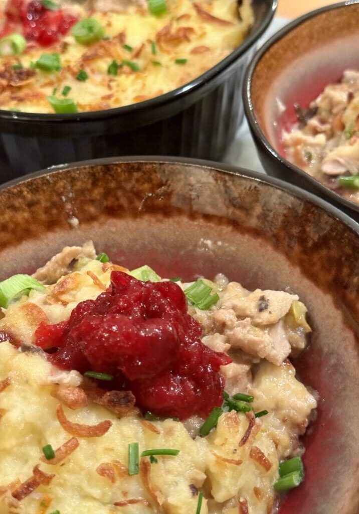 Bowl of creamy chicken dish with cranberry sauce.