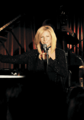 A woman singing into a microphone in front of a crowd.